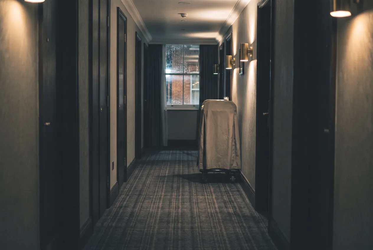 A housekeeping trolley in a lamplit hotel corridor