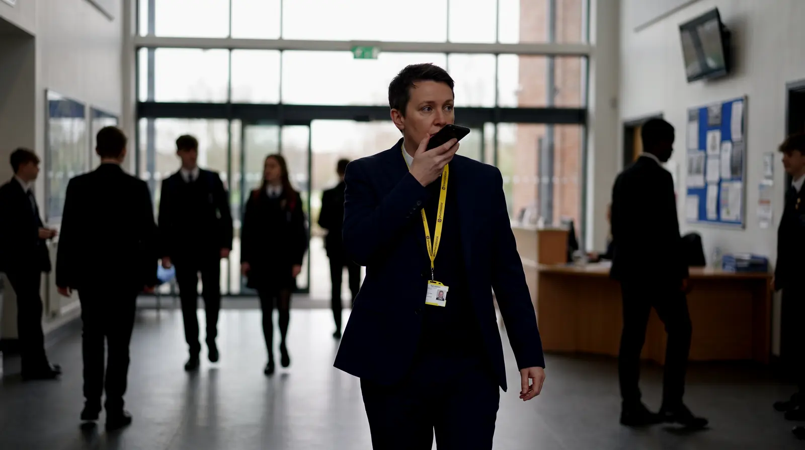 A staff member on a radio in a school atrium as pupils move between lessons
